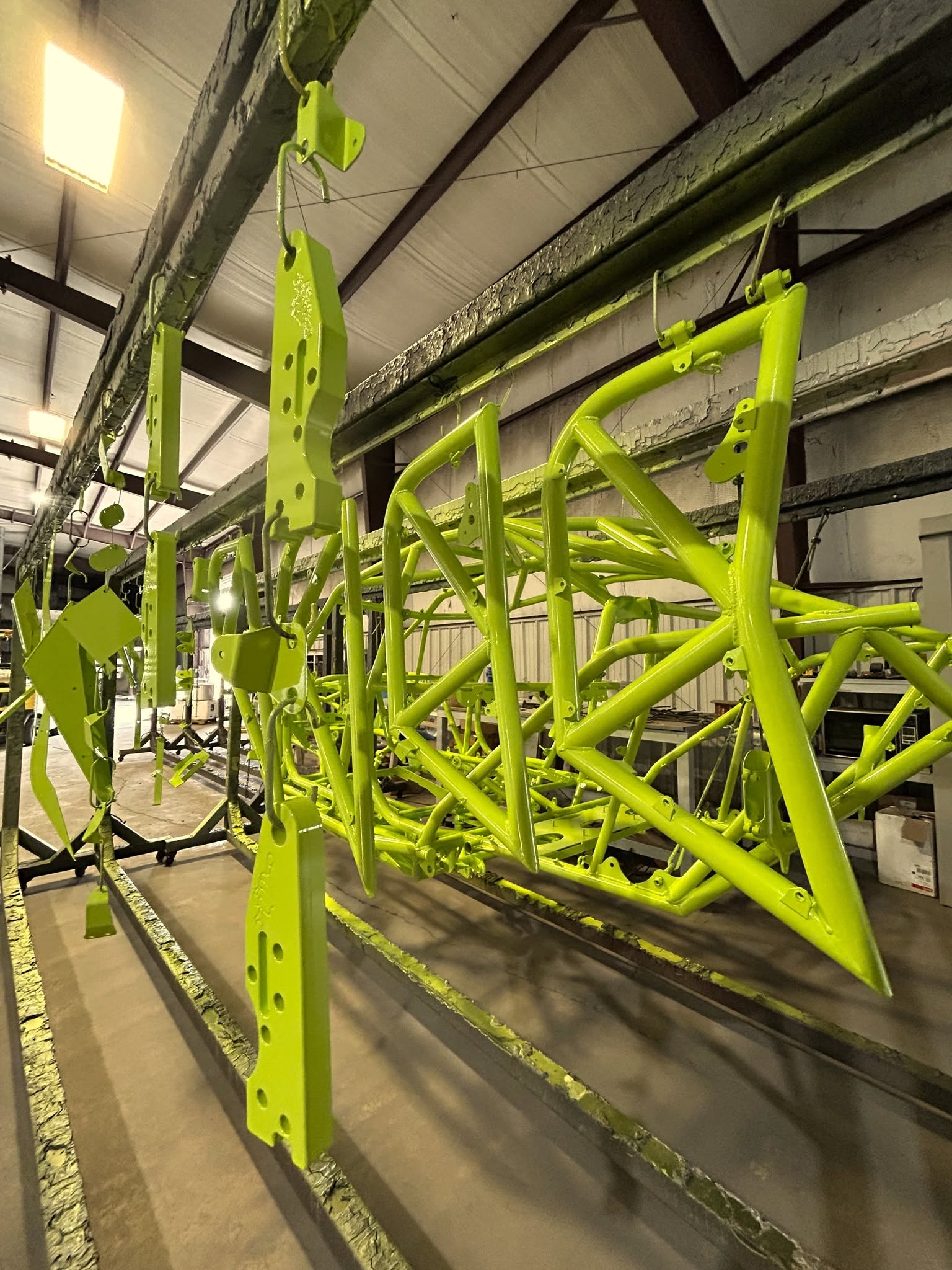 A powder-coated tube chassis in high-visibility green moving through the PowderTec line in Cullman, Alabama