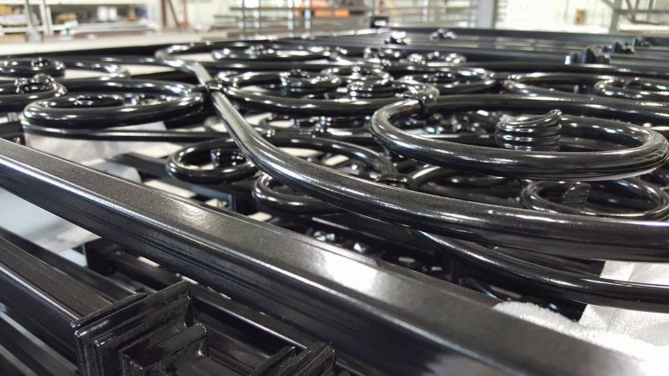 Ornamental steel railing sections in a deep gloss black powder coat, staged on the shop floor