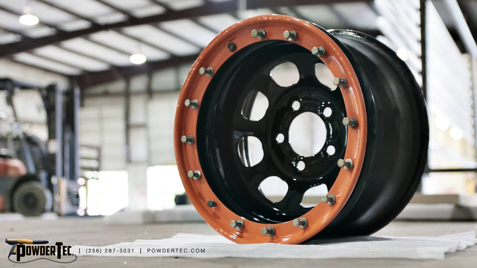 A steel beadlock wheel finished in gloss black with a burnt-orange beadlock ring